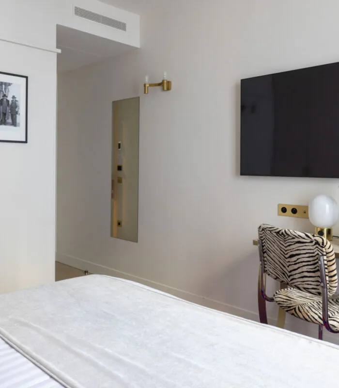 Chambre Double Standard Bouglione avec une chaise à motif zèbre et une télévision à écran plat à l’hôtel Astra Opéra