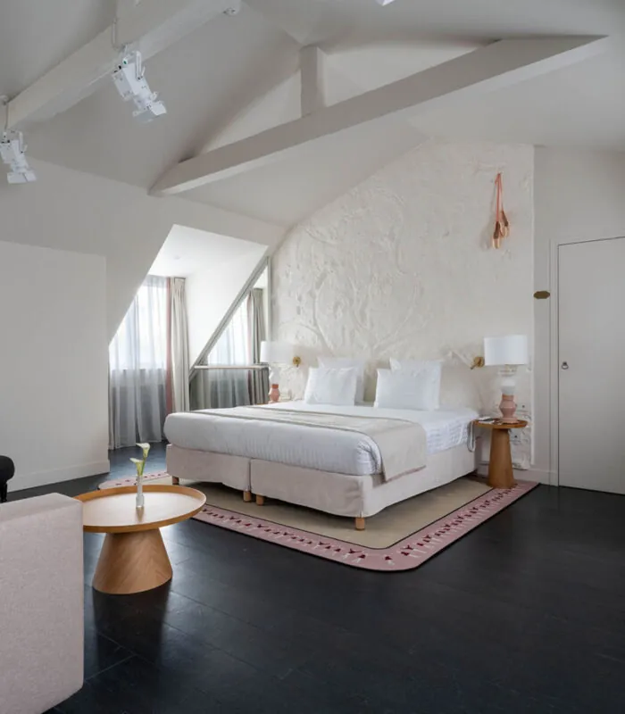 Chambre Exécutive Marie-Agnès Gillot avec un grand lit et un fauteuil à l’hôtel Astra Opéra