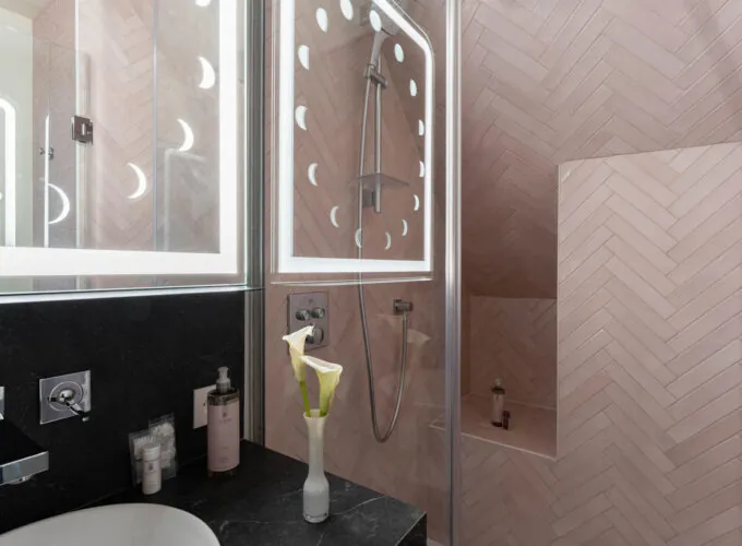 Salle de bain Exécutive Marie-Agnès Gillot avec des carreaux roses et une douche à l’hôtel Astra Opéra