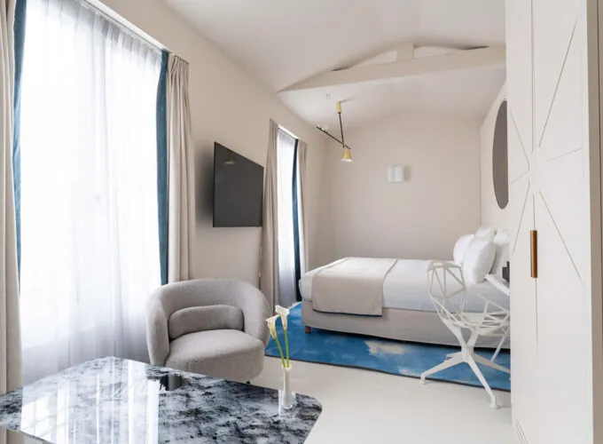 Chambre Triple Claudie Haigneré avec un lit, une chaise et une télévision à l’hôtel Astra Opéra