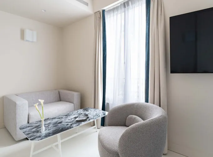 Salon de la chambre Triple Claudie Haigneré avec un canapé et une chaise à l’hôtel Astra Opéra