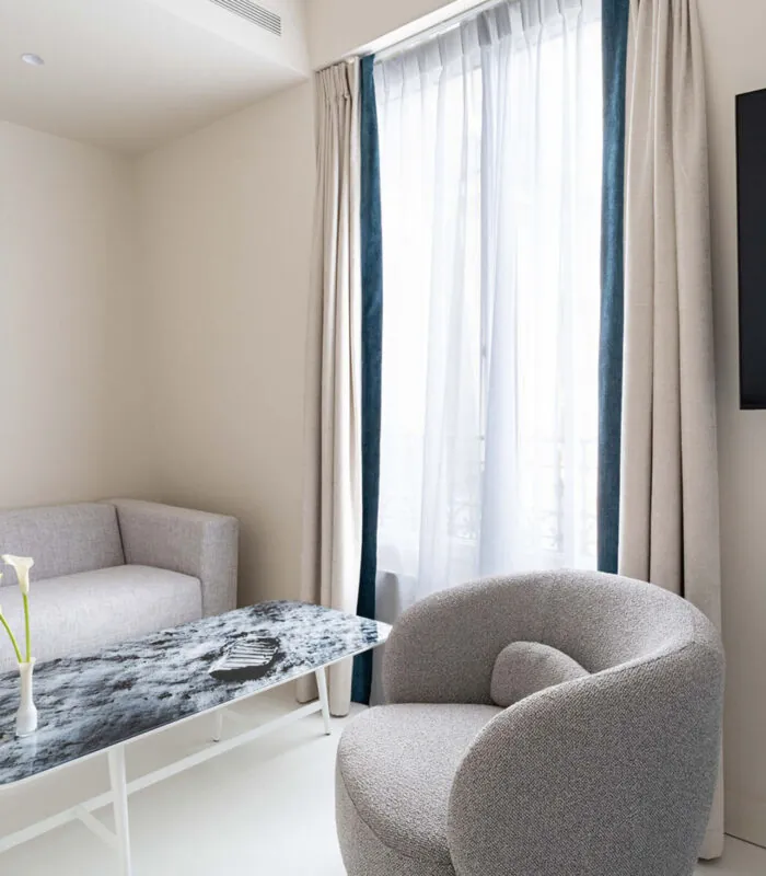 Salon de la chambre Triple Claudie Haigneré avec un canapé et une chaise à l’hôtel Astra Opéra