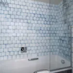 Salle de bain de la chambre Triple Claudie Haigneré avec des carreaux bleus et blancs et une baignoire à l’hôtel Astra Opéra