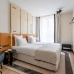 Chambre Twin Standard Daniel Auteuil avec deux lits et un mur à l’hôtel Astra Opéra