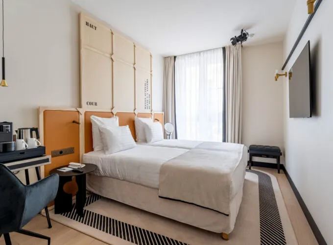 Chambre Twin Standard Daniel Auteuil avec deux lits et un mur à l’hôtel Astra Opéra