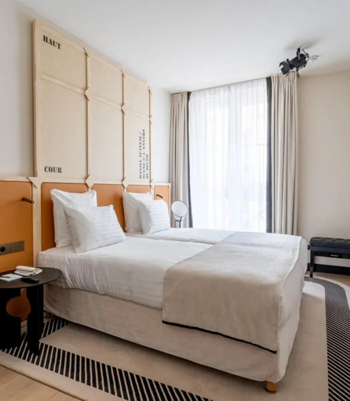 Chambre Twin Standard Daniel Auteuil avec deux lits et un mur à l’hôtel Astra Opéra