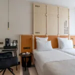 Chambre Twin Standard Daniel Auteuil avec deux lits et un mur à l’hôtel Astra Opéra