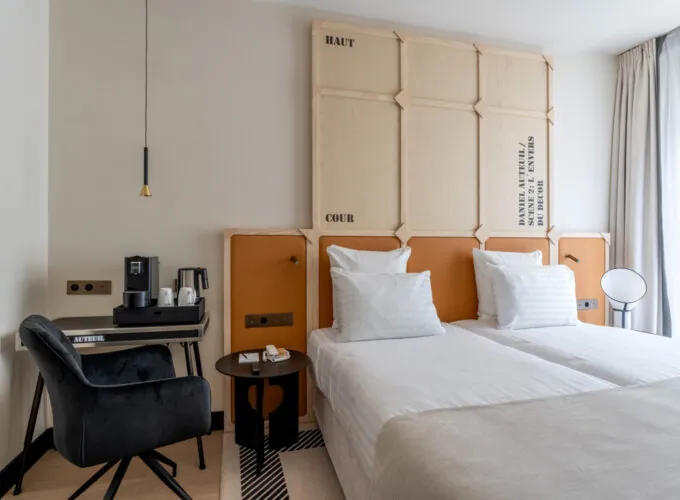 Chambre Twin Standard Daniel Auteuil avec deux lits et un mur à l’hôtel Astra Opéra
