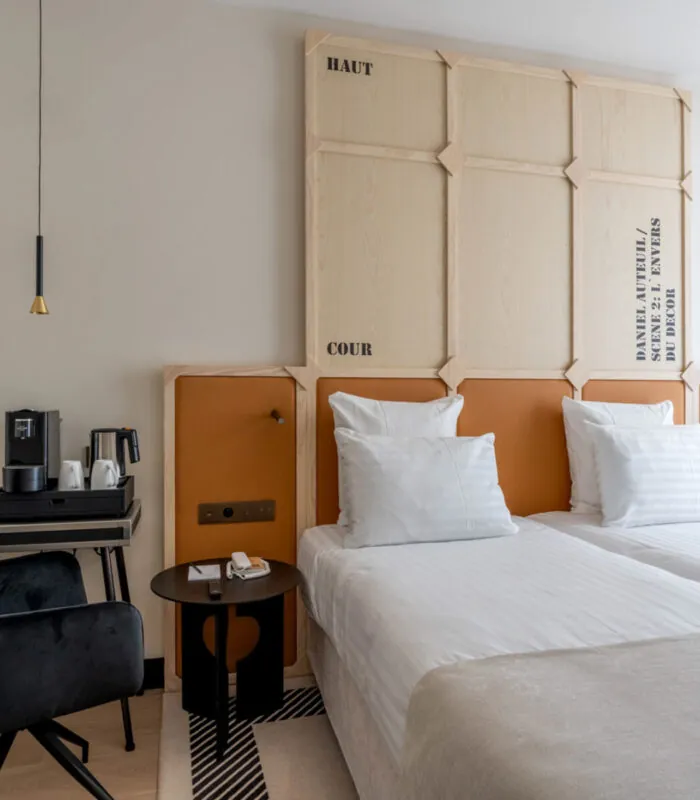 Chambre Twin Standard Daniel Auteuil avec deux lits et un mur à l’hôtel Astra Opéra