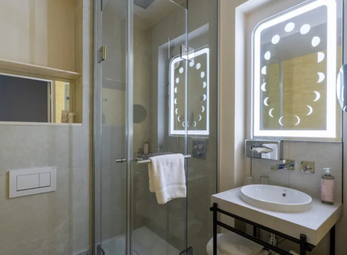 Salle de bain Twin Standard Daniel Auteuil avec un lavabo, un miroir et une douche à l’hôtel Astra Opéra