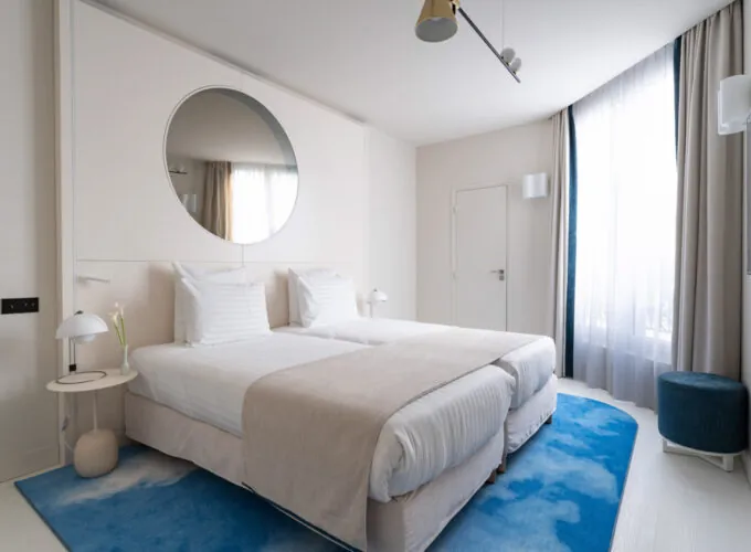 Chambre Twin Supérieure Claudie Haigneré avec deux lits et un tapis bleu à l’hôtel Astra Opéra
