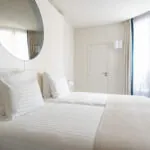 Chambre Twin Supérieure Claudie Haigneré avec deux lits et un grand miroir à l’hôtel Astra Opéra