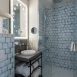 Salle de bain Twin Supérieure Claudie Haigneré avec des carreaux bleus, un lavabo et une douche à l’hôtel Astra Opéra