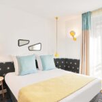 Chambre Double avec un lit et deux miroirs au mur à l’hôtel Augustin