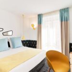 Chambre Double avec un grand lit et une chaise jaune à l’hôtel Augustin