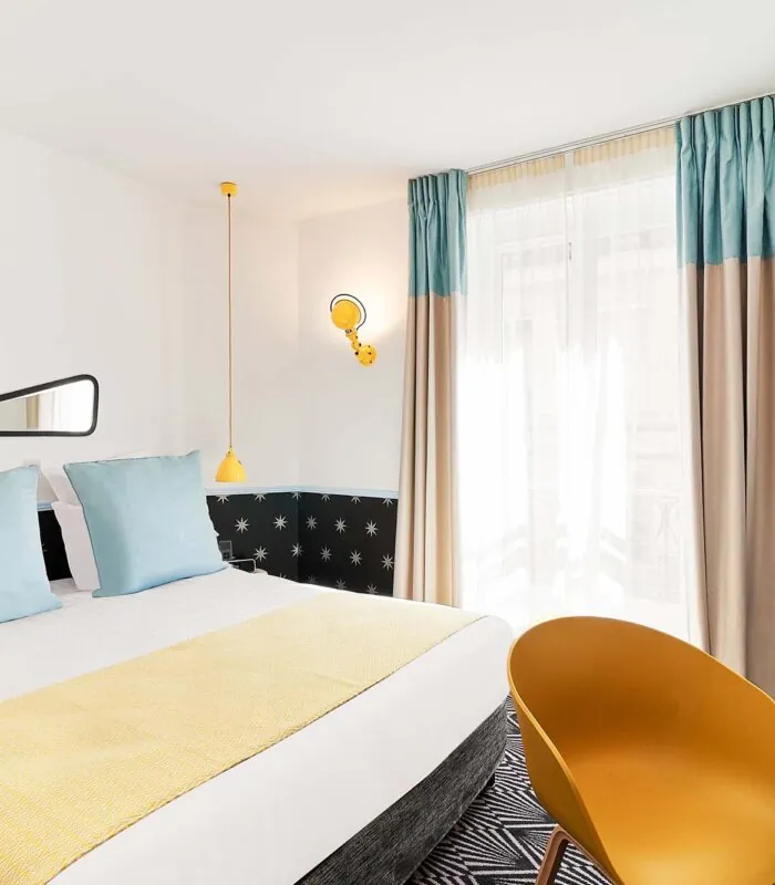 Chambre Double avec un grand lit et une chaise jaune à l’hôtel Augustin