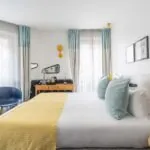 Chambre Familiale avec un grand lit et une chaise bleue à l’hôtel Augustin