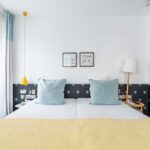 Chambre Familiale avec un lit et deux tableaux accrochés au mur à l’hôtel Augustin