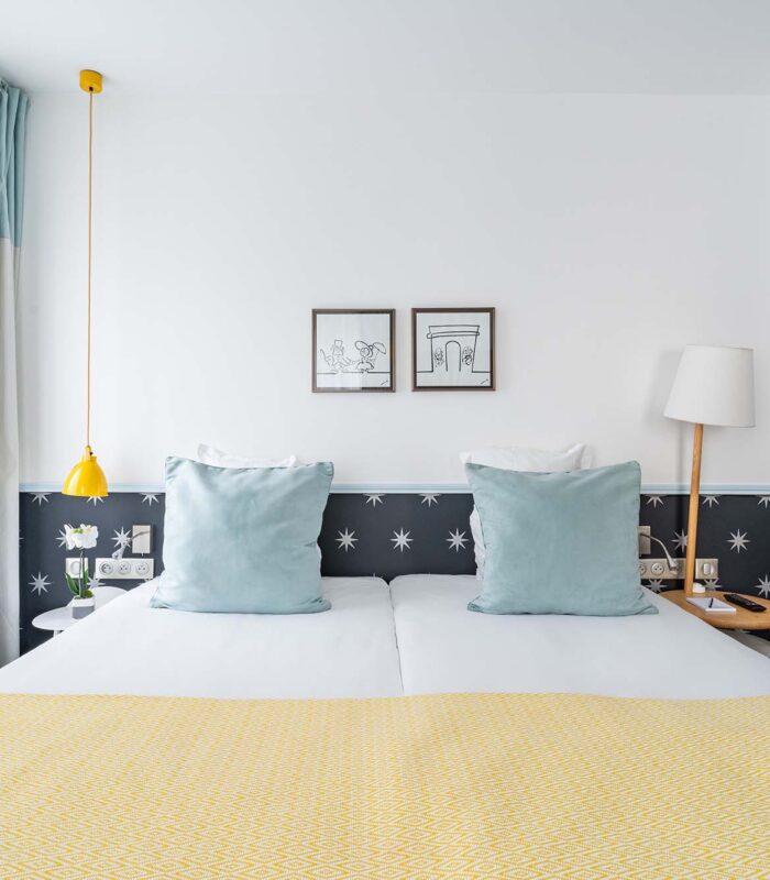 Chambre Familiale avec un lit et deux tableaux accrochés au mur à l’hôtel Augustin