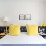 Chambre Familiale avec un lit et deux tableaux accrochés au mur à l’hôtel Augustin