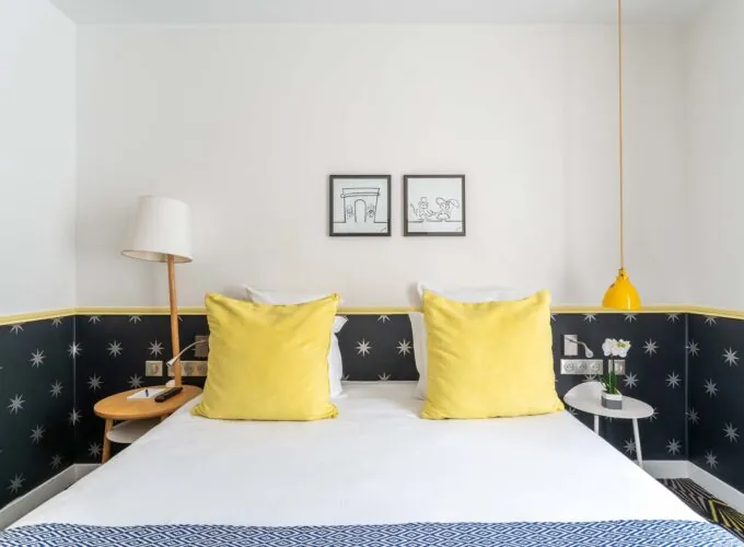 Chambre Familiale avec un lit et deux tableaux accrochés au mur à l’hôtel Augustin