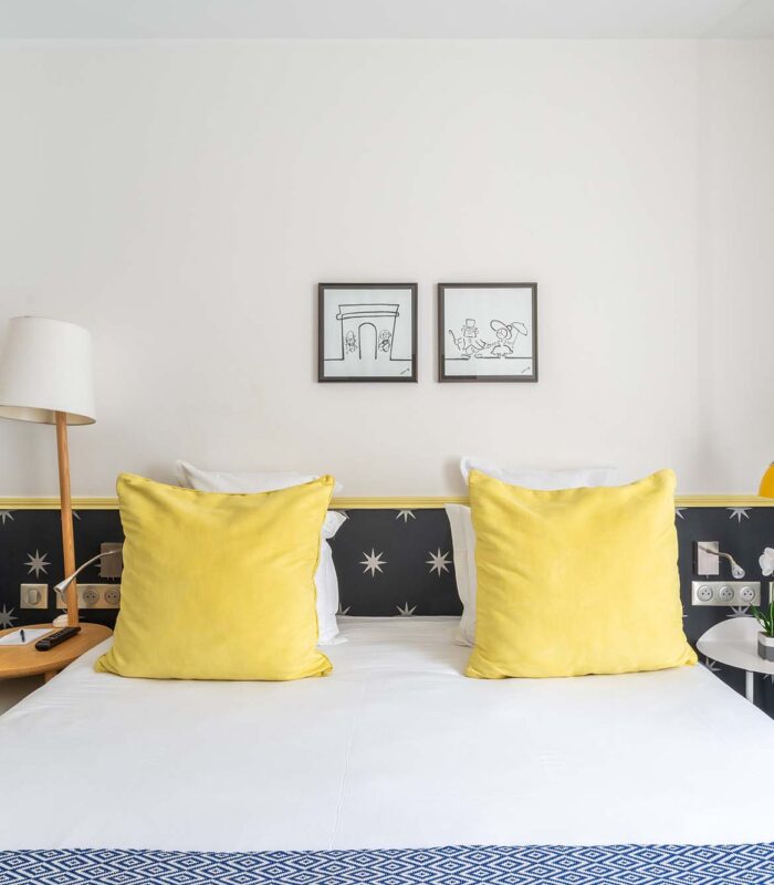 Chambre Familiale avec un lit et deux tableaux accrochés au mur à l’hôtel Augustin