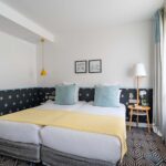 Chambre Privilège avec un lit et deux tableaux au mur à l’Hôtel Augustin