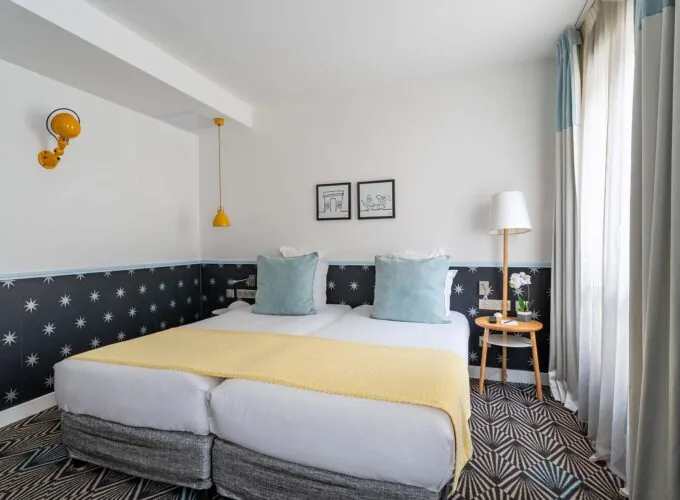 Chambre Privilège avec un lit et deux tableaux au mur à l’Hôtel Augustin