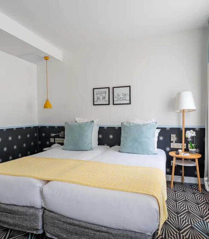 Chambre Privilège avec un lit et deux tableaux au mur à l’Hôtel Augustin