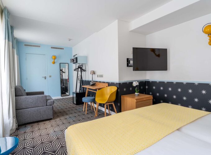 Chambre Privilège avec un lit, un bureau et une télévision à écran plat à l’Hôtel Augustin