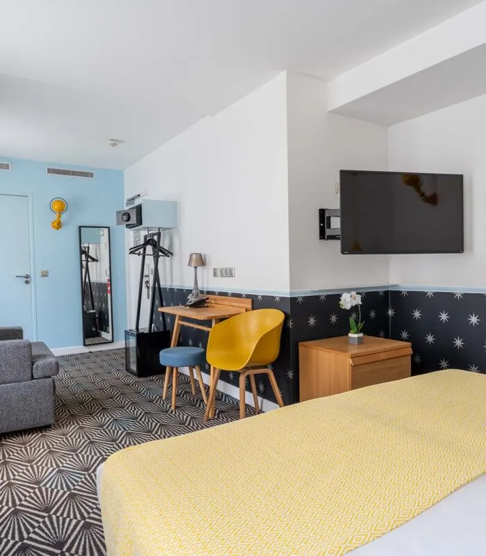 Chambre Privilège avec un lit, un bureau et une télévision à écran plat à l’Hôtel Augustin