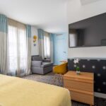 Chambre Privilège avec une grande télévision à écran plat fixée au mur à l’Hôtel Augustin