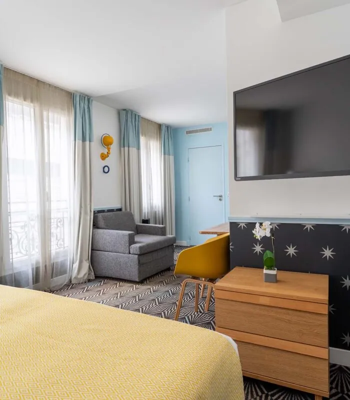 Chambre Privilège avec une grande télévision à écran plat fixée au mur à l’Hôtel Augustin