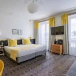 Chambre Quadruple avec un grand lit et une télévision à écran plat à l’hôtel Augustin