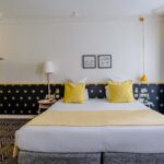 Chambre Quadruple avec un lit et des oreillers jaunes à l’hôtel Augustin