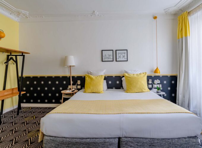 Chambre Quadruple avec un lit et des oreillers jaunes à l’hôtel Augustin