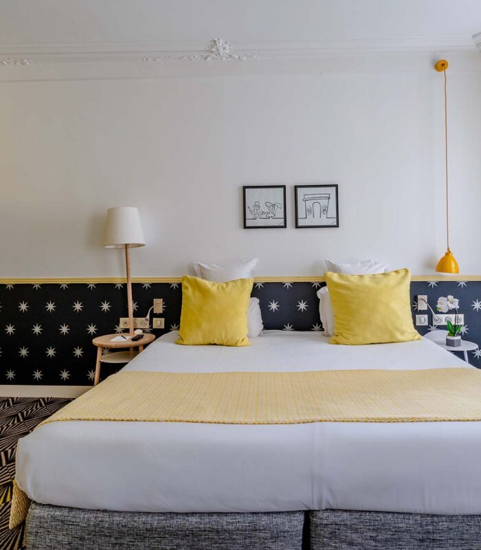 Chambre Quadruple avec un lit et des oreillers jaunes à l’hôtel Augustin