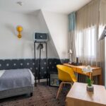 Chambre Single Cocoon avec un lit simple et un bureau à l’hôtel Augustin