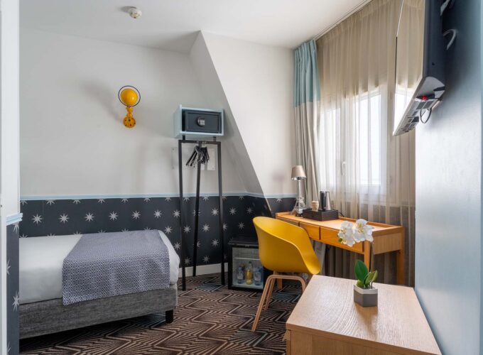 Chambre Single Cocoon avec un lit simple et un bureau à l’hôtel Augustin