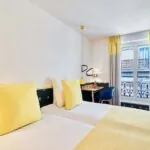 Chambre Twin avec deux lits et un bureau à l’hôtel Augustin