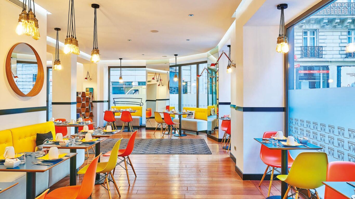 Salle de petit-déjeuner de l’hôtel Augustin à Paris avec buffet varié, atmosphère chaleureuse et touches de couleurs vives
