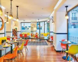 Salle de petit-déjeuner de l’hôtel Augustin à Paris avec buffet varié, atmosphère chaleureuse et touches de couleurs vives
