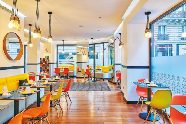 Salle de petit-déjeuner de l’hôtel Augustin à Paris avec buffet varié, atmosphère chaleureuse et touches de couleurs vives