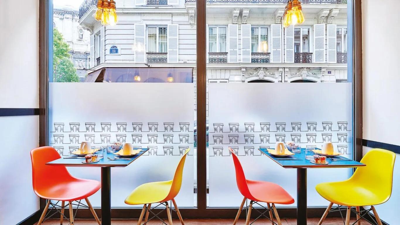 Salle de petit-déjeuner de l’hôtel Augustin à Paris avec un buffet varié, une atmosphère chaleureuse et des touches de couleur vives