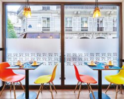 Salle de petit-déjeuner de l’hôtel Augustin à Paris avec un buffet varié, une atmosphère chaleureuse et des touches de couleur vives