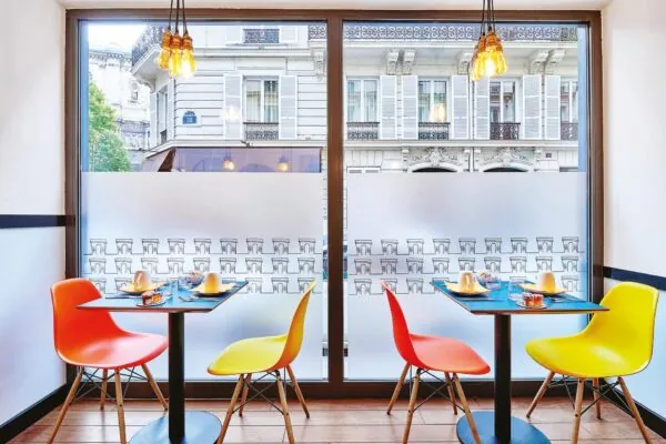 Salle de petit-déjeuner de l’hôtel Augustin à Paris avec un buffet varié, une atmosphère chaleureuse et des touches de couleur vives