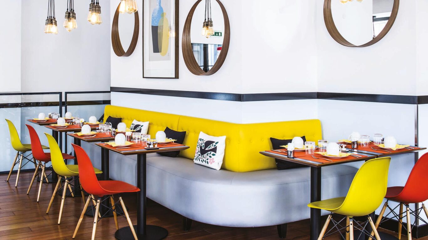 Salle de petit-déjeuner de l’hôtel Augustin à Paris avec buffet varié, atmosphère chaleureuse et touches de couleurs vives