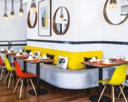 Salle de petit-déjeuner de l’hôtel Augustin à Paris avec buffet varié, atmosphère chaleureuse et touches de couleurs vives