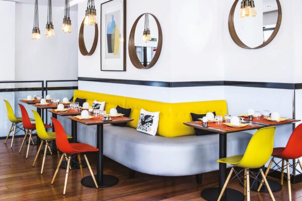 Salle de petit-déjeuner de l’hôtel Augustin à Paris avec buffet varié, atmosphère chaleureuse et touches de couleurs vives