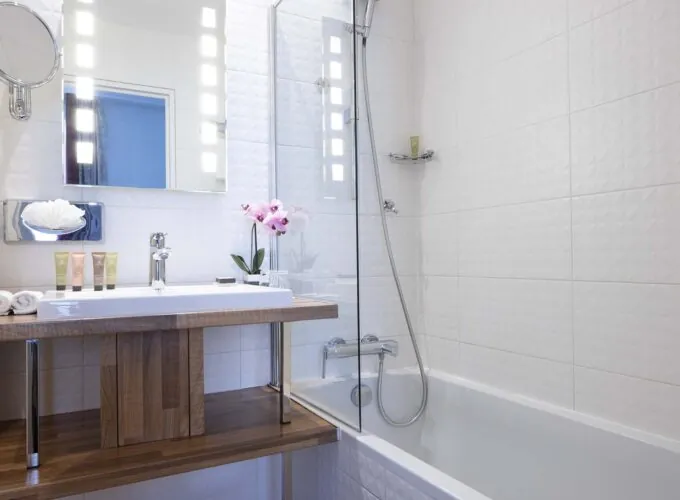 Chambre Double bathroom with a sink a mirror and a bathtub at the Hotel Bradford Elysees